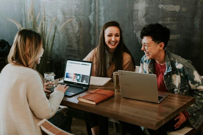 a group of people sitting at a table using a laptop
