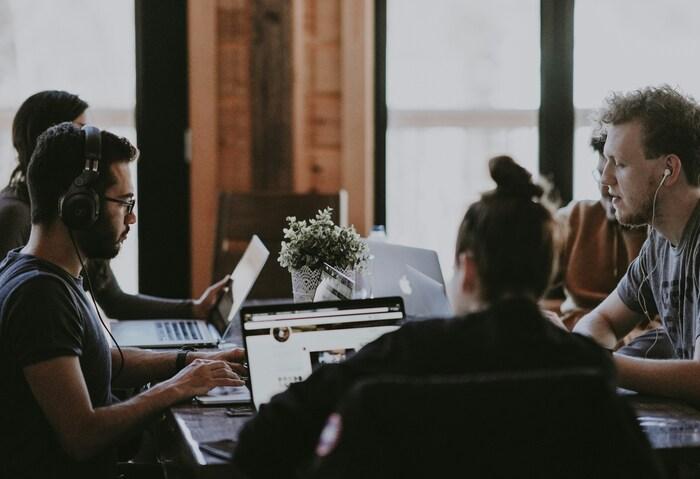 a man and a woman sitting at a table looking at a laptop
