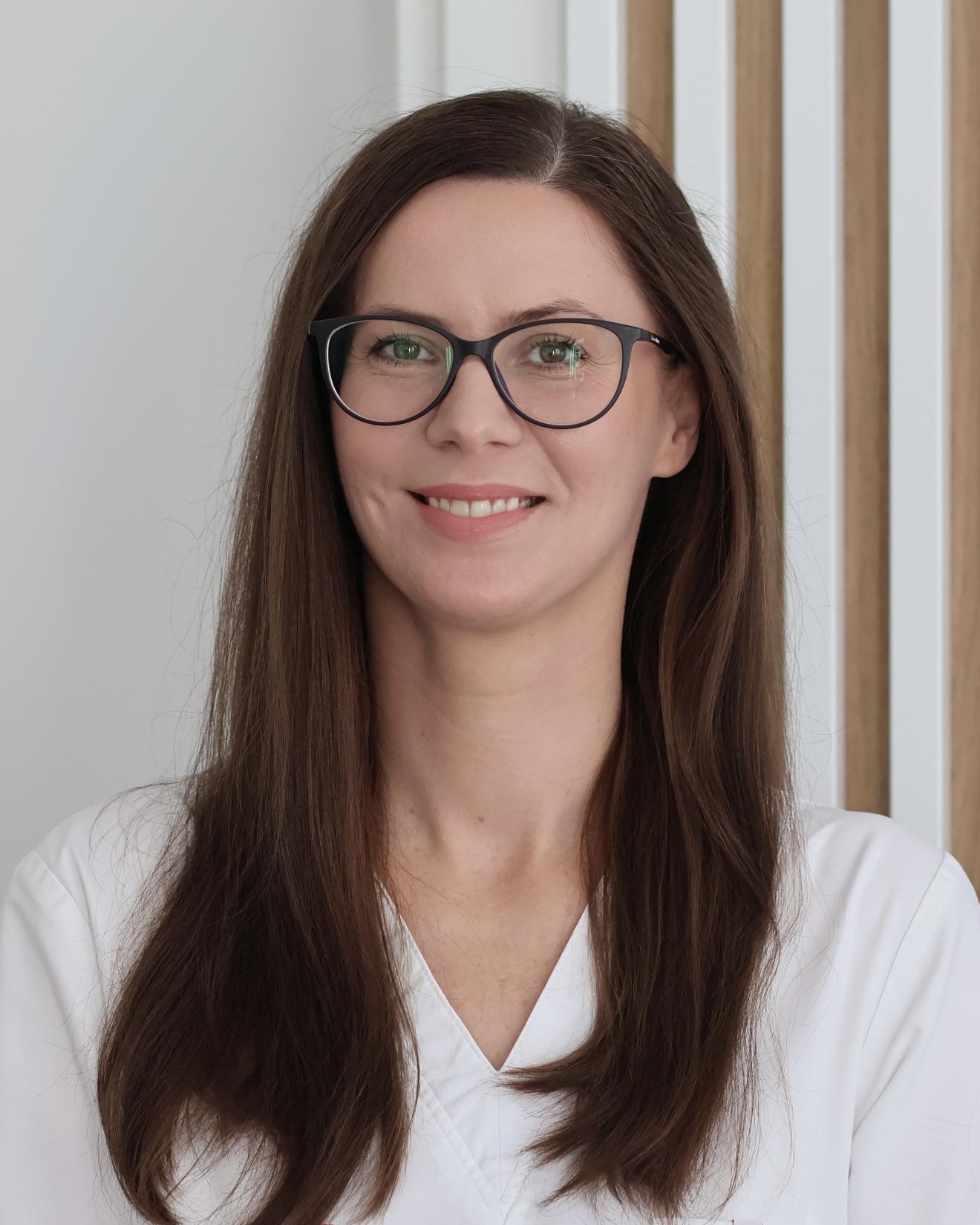 a woman wearing glasses and smiling at the camera